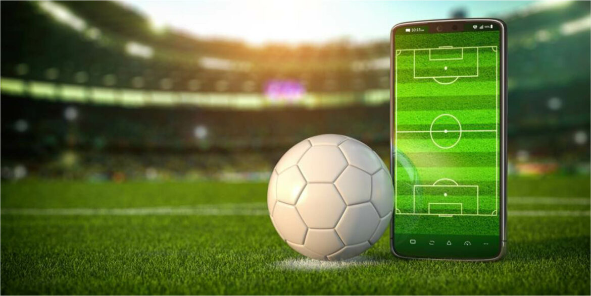 Campo de futebol com bola e celular em destaque